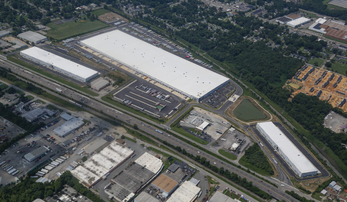 Aerial view: large warehouse complex with white roofs and surroundings.