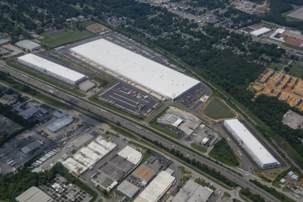 Aerial view: large warehouse complex with white roofs and surroundings.