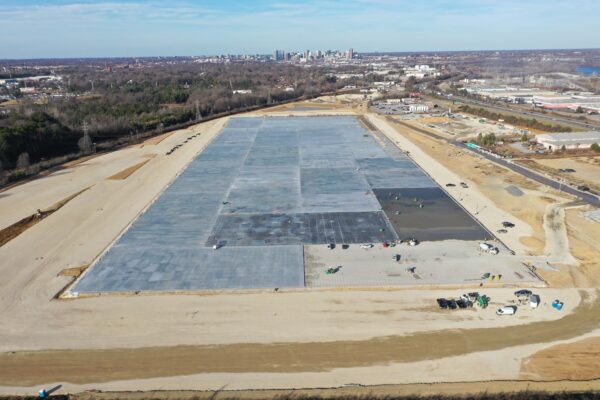 Construction site with concrete foundation, dirt, vehicles, city skyline.