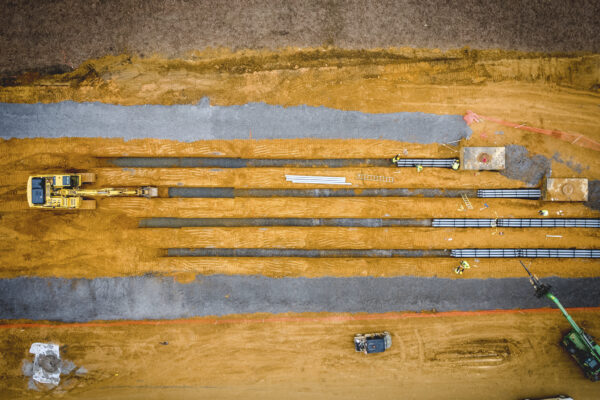 Aerial view: construction site with machines, steel beams, workers.