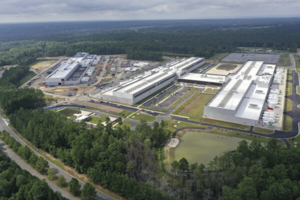 Aerial view of industrial facility with white buildings and ponds.