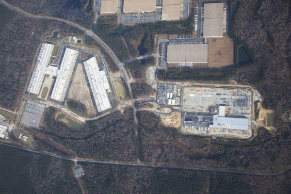 Aerial view of warehouses, parking lots, construction, and woods.