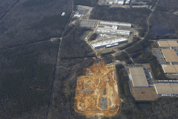 Aerial view: construction site, forest, nearby factories.