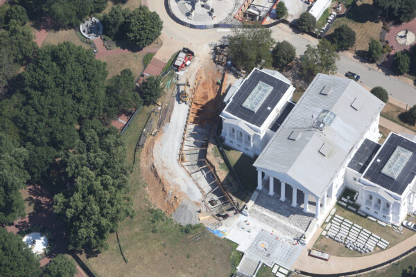 Aerial view: large, columned building under construction with vehicles.