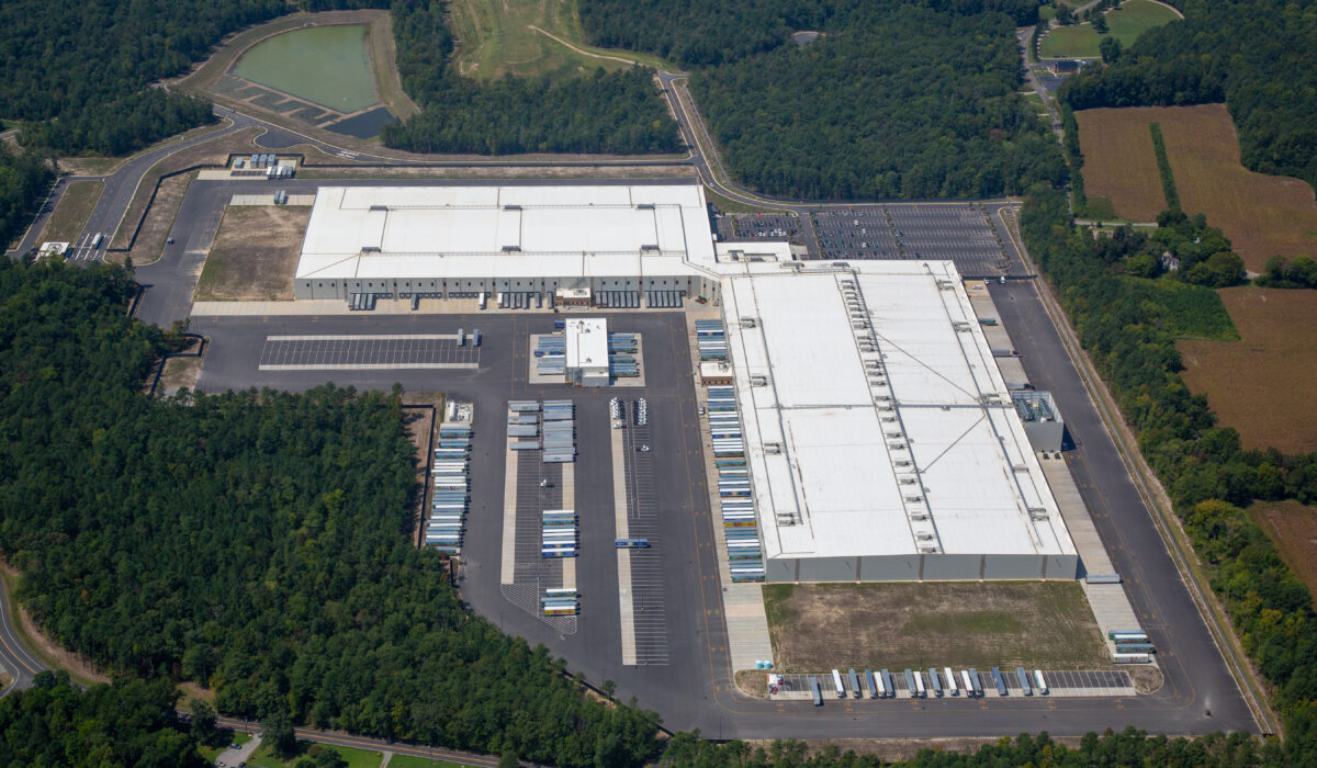 Aerial view of a warehouse with docks, trucks, and trees.