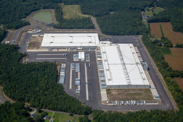 Aerial view of a warehouse with docks, trucks, and trees.