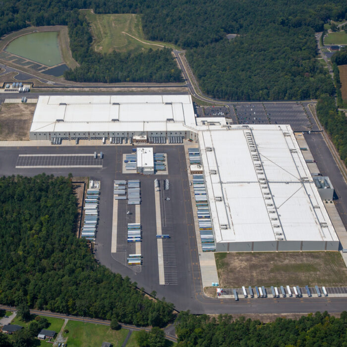 Aerial view of a warehouse with docks, trucks, and trees.