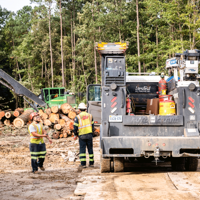 Two workers in vests stand by a utility truck.