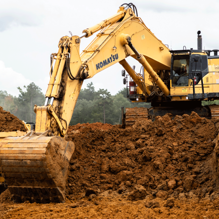 Yellow Komatsu excavator loads dirt into dump truck onsite.