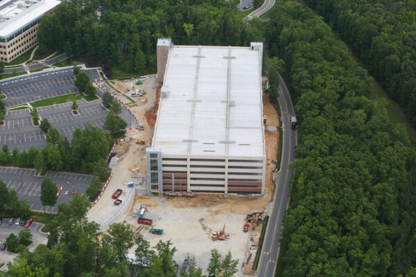 Aerial view: multi-level parking garage under construction near trees.