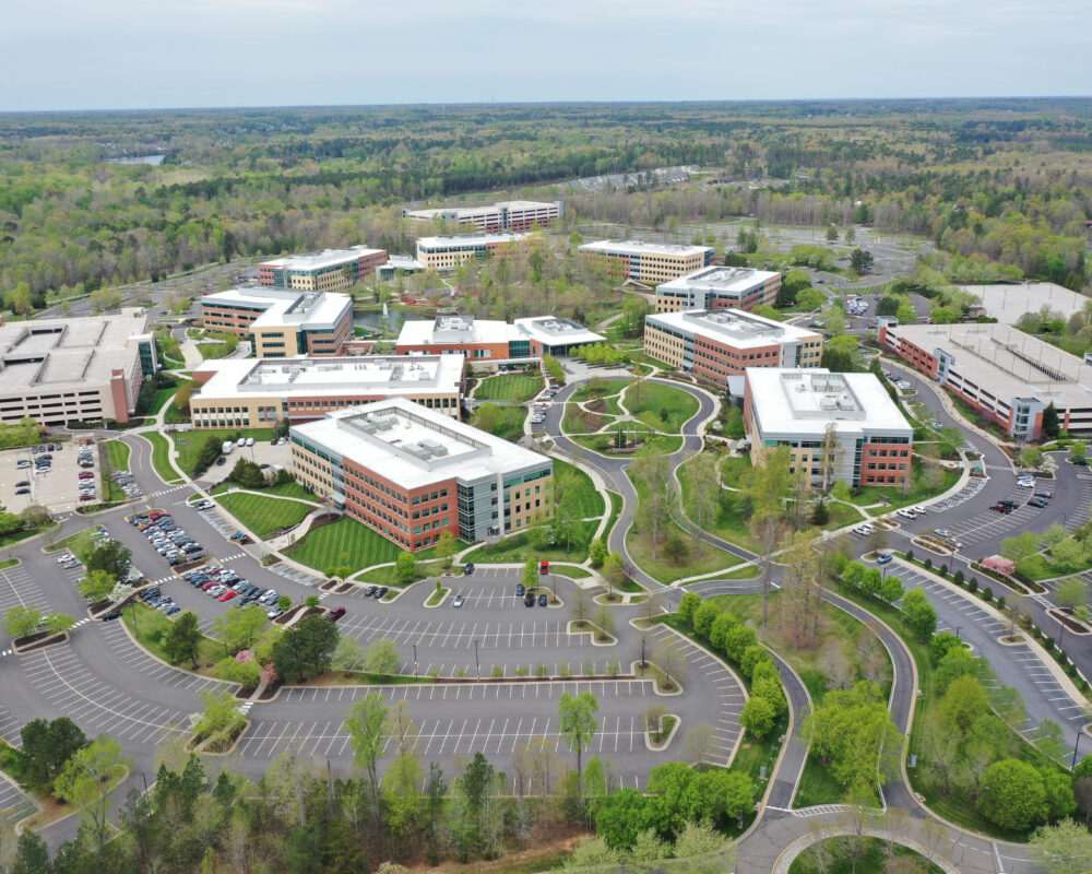 Aerial view of modern office park, greenery, and parking lots.