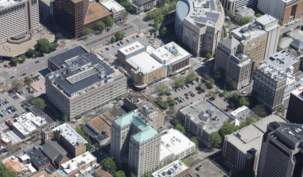 Aerial view of downtown with mid-rises, streets, and trees.