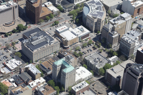 Aerial view of downtown with mid-rises, streets, and trees.