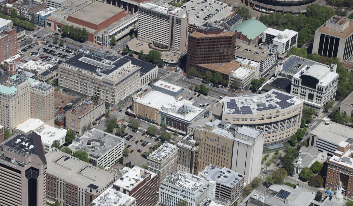 Aerial view: downtown offices, parking, trees, arena top-right.