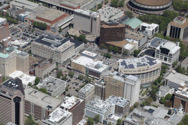 Aerial view: downtown offices, parking, trees, arena top-right.