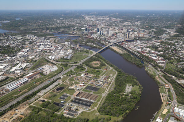 City aerial: river, bridges, industry, green spaces, dense buildings.
