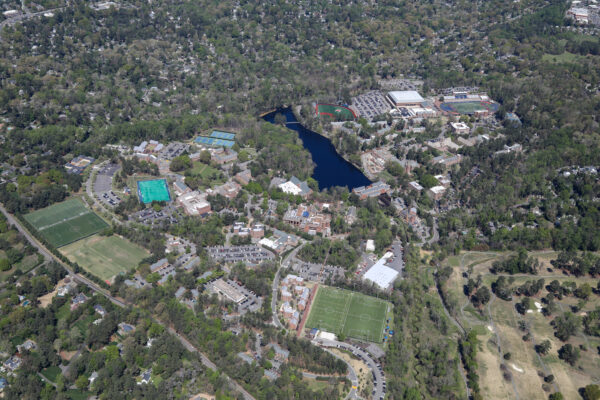 Aerial view: campus with buildings, fields, lake, greenery.