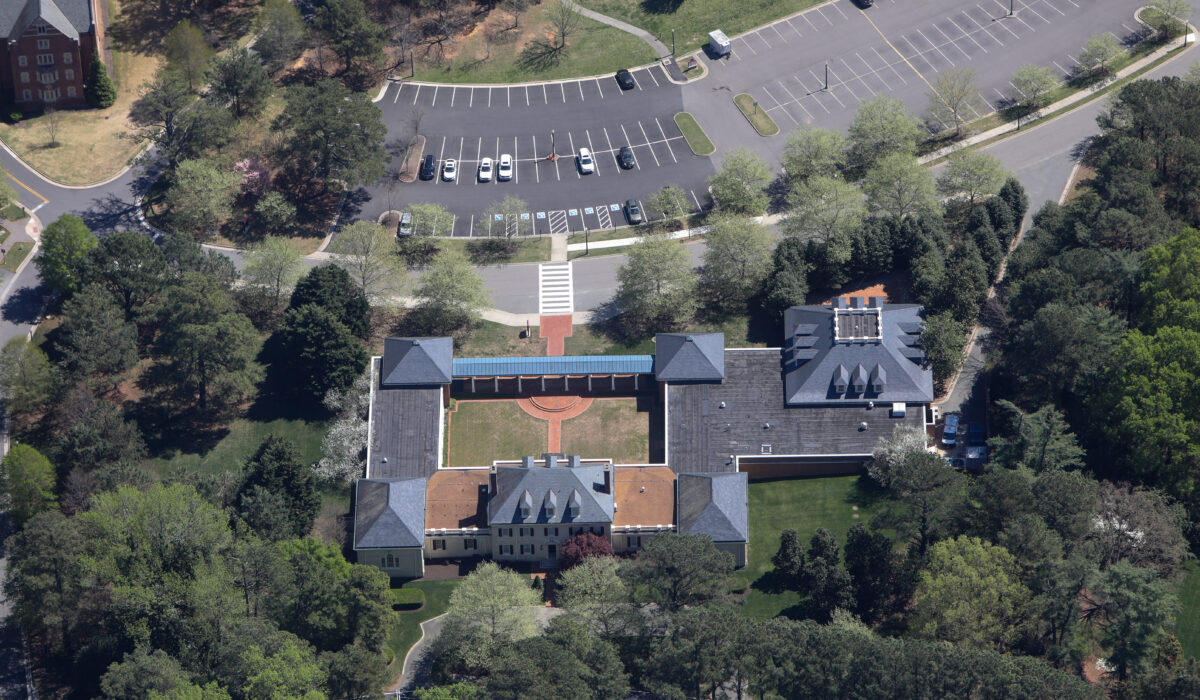 Aerial view: building with courtyard, trees, parking lot, cars.