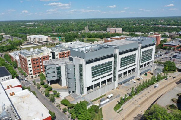 Aerial view of modern hospital, trees, parking lots, and buildings.