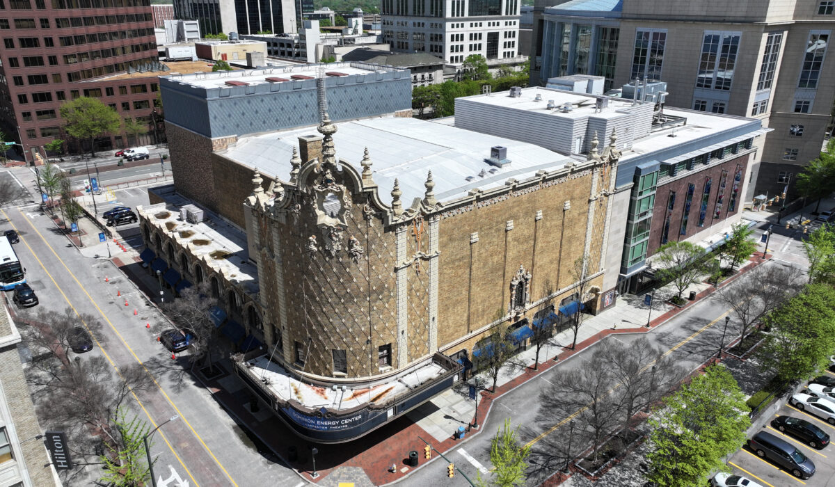 Aerial view: ornate historic theater amid modern buildings and trees.
