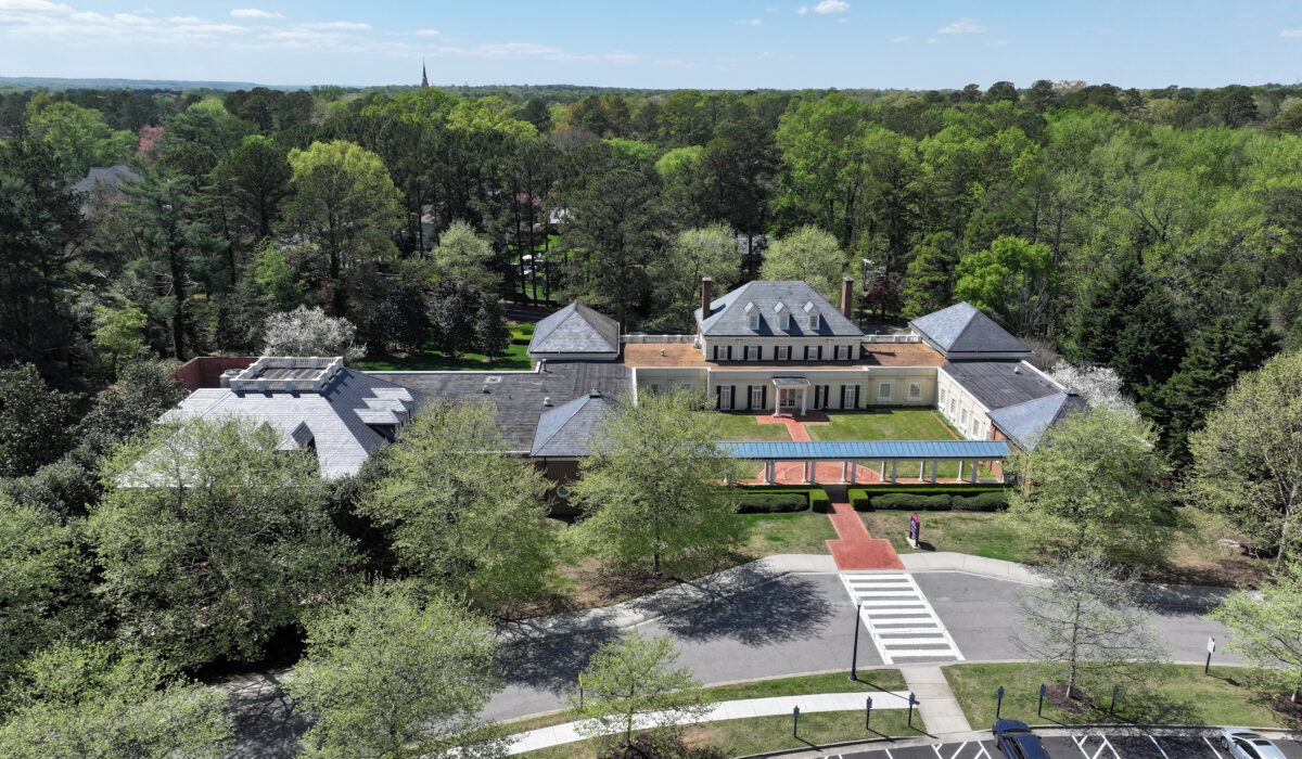 Aerial view of large building with courtyard and parking.