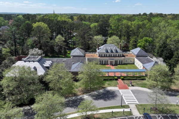Aerial view of large building with courtyard and parking.