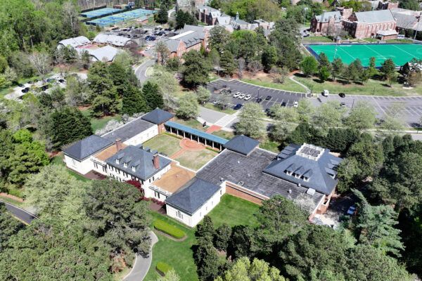 Campus drone view: buildings, courtyard, parking, sports fields, trees.