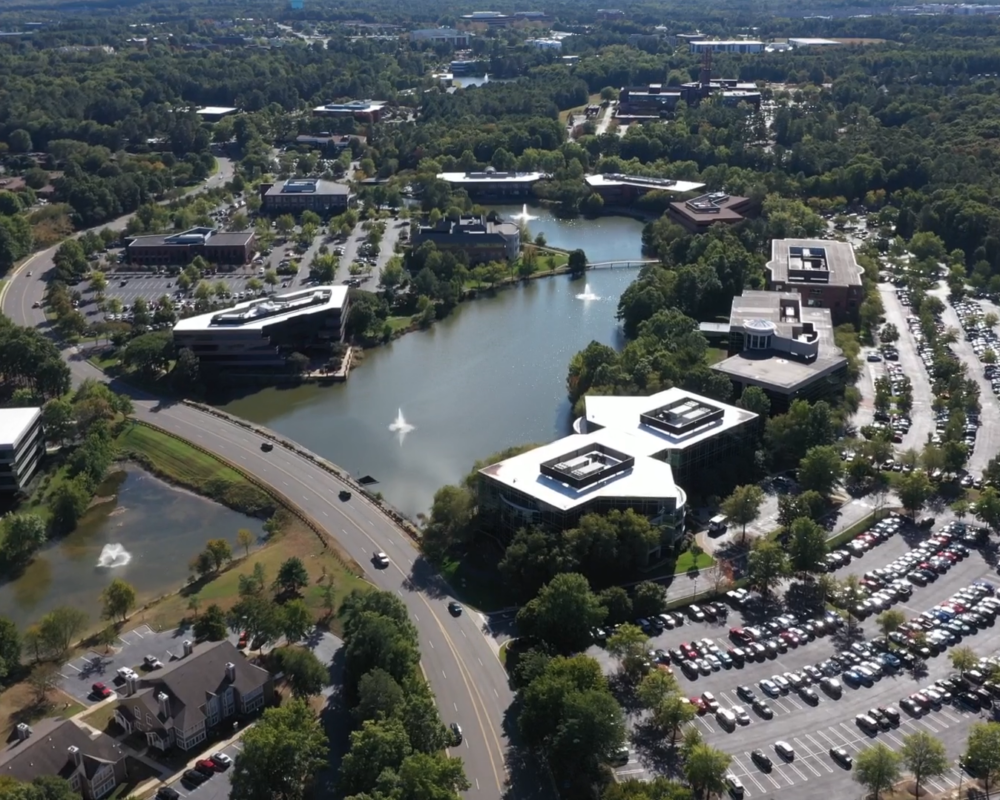 Aerial view of modern office park, greenery, and parking lots.