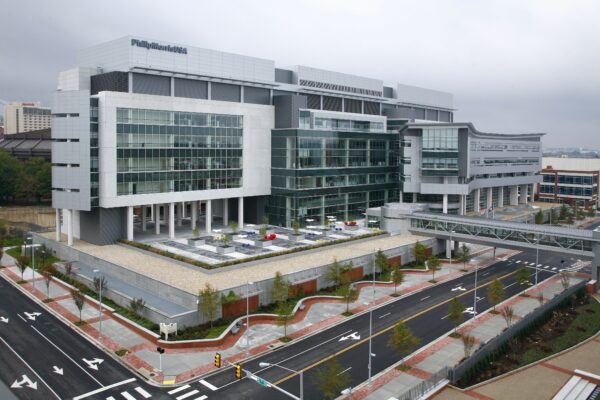 Modern multi-story hospital with glass windows, empty streets, overcast.