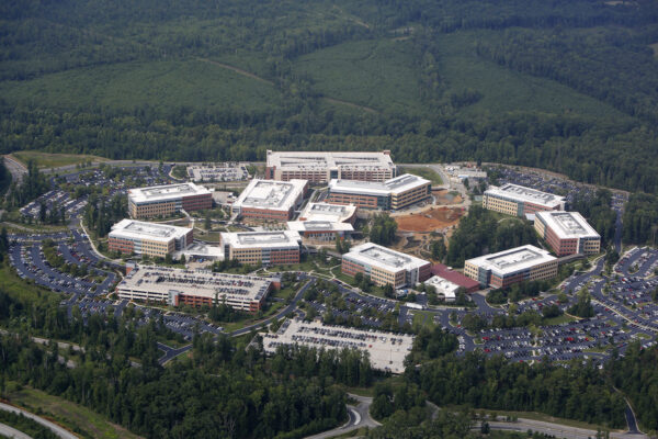 Aerial view of office complex, parking lots, and forest.