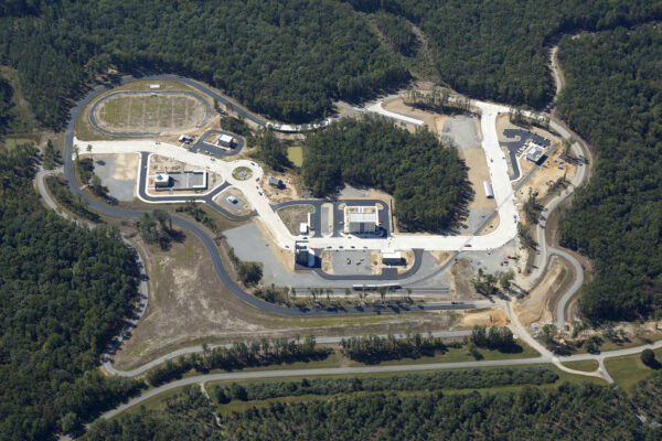 Aerial view: large, unfinished facility amid forests and clearings.