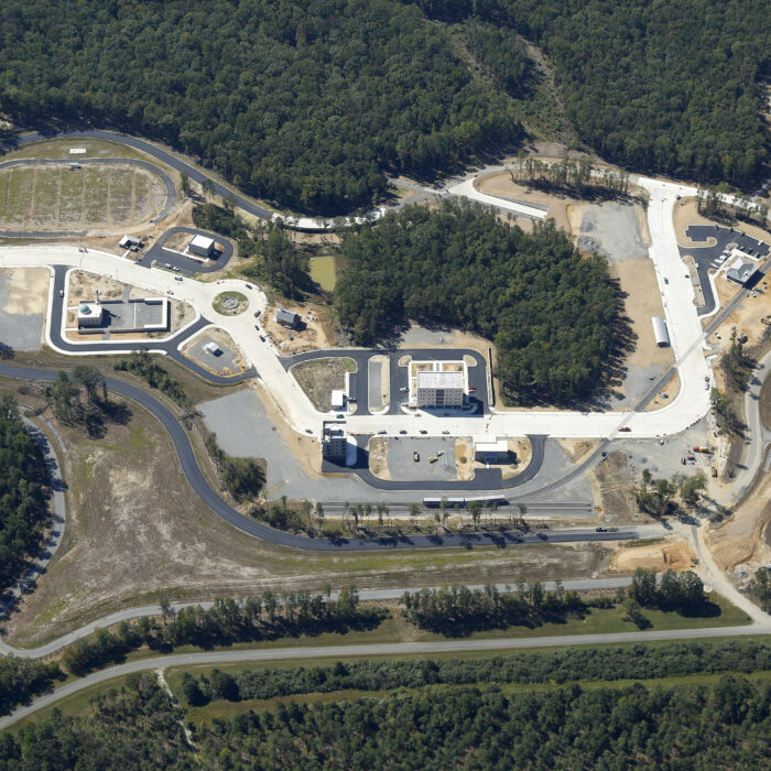 Aerial view: large, unfinished facility amid forests and clearings.
