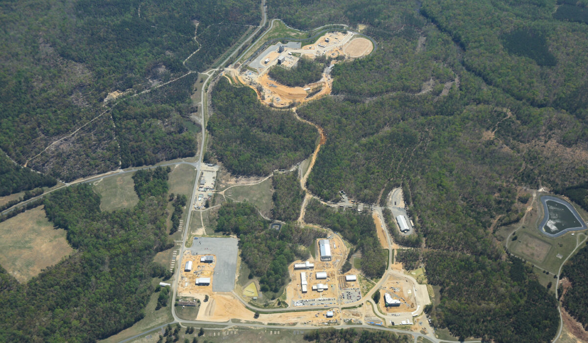 Aerial view: training facility amid forest, with roads and buildings.