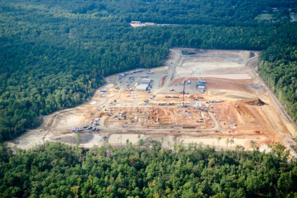 Aerial view: large construction site amid dense forest.