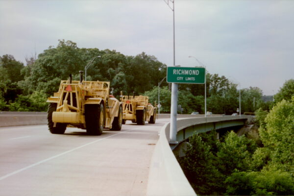 Two yellow construction vehicles cross a bridge into Richmond.