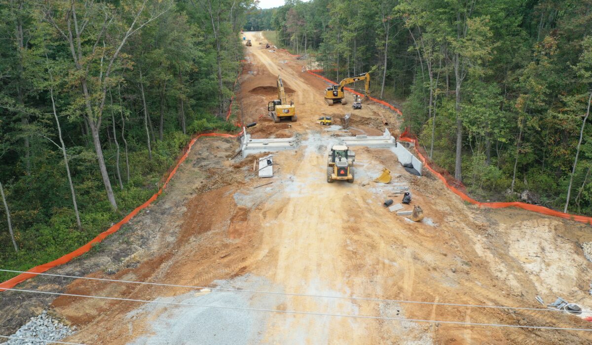 Construction site with machinery and barriers in a forest.