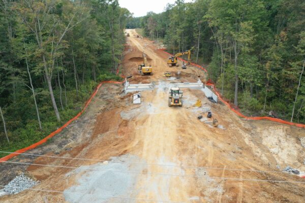 Construction site with machinery and barriers in a forest.