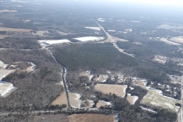 Aerial view of snowy rural land with roads and buildings.