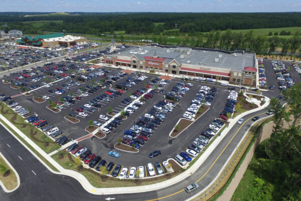 Aerial view of big shopping center, many cars, green areas.