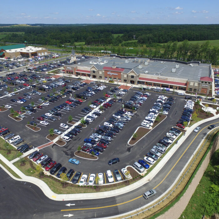 Aerial view of big shopping center, many cars, green areas.
