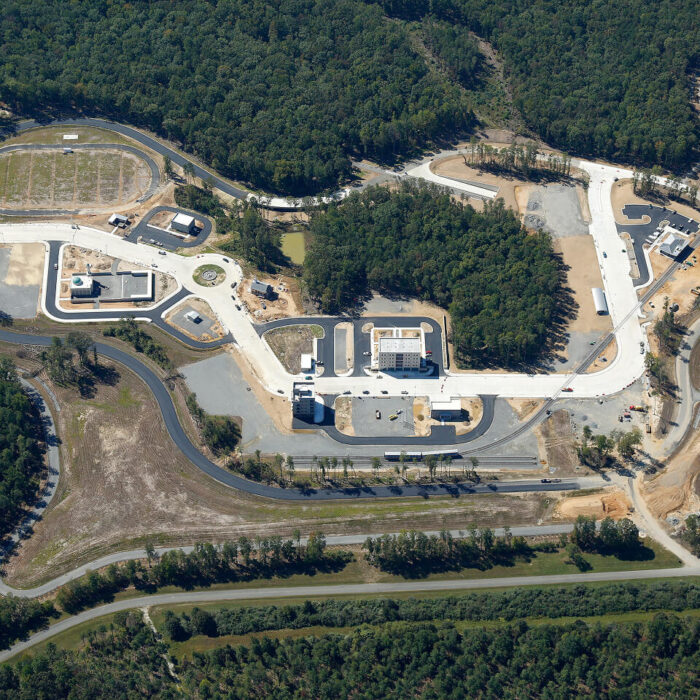 Aerial view: large modern complex amid dense forest.